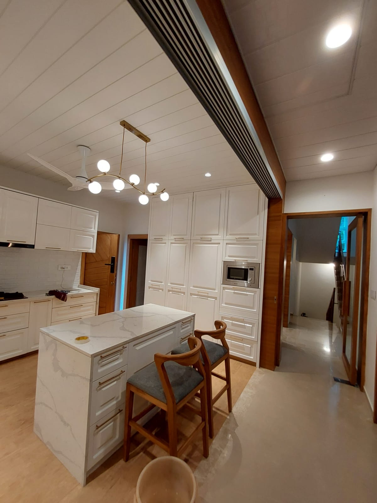 White kitchen with island seating & gold pendant lights